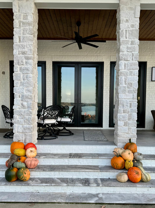 Decorative arrangement of pumpkins on a staircase leading to a modern house entrance.